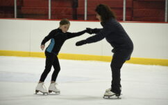 Instructor helping a young skater balance.